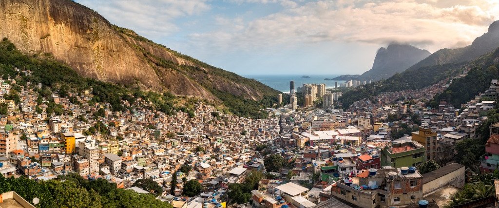 Panoramic view of the Rocinha favela in Rio de Janeiro, with mountains and the ocean behind it