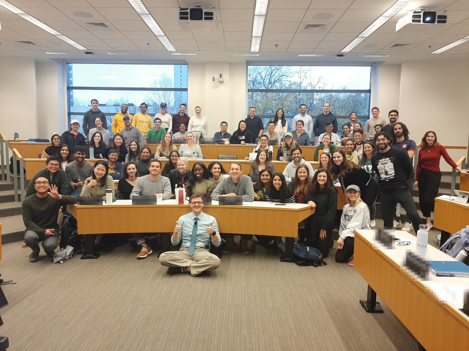 Leandro Pongeluppe sitting on the classroom floor with his Wharton MBA class of MGMT 6110 in a tiered lecture hall, Fall 2022